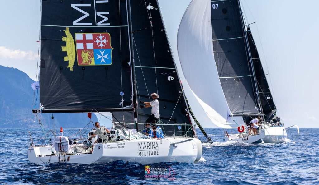 Two double-handed boats sailing on a reach, hoisting their spinnakers.