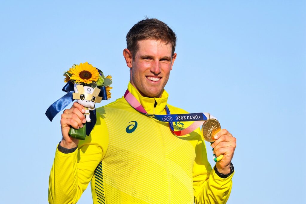 Matt Wearn holding up his medal and flowers at the medal ceremony. 