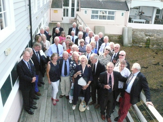 The men and women smiling outside on the balcony.