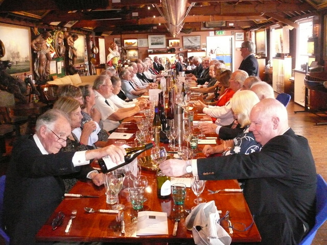 Long, packed table, two people pouring drinks.