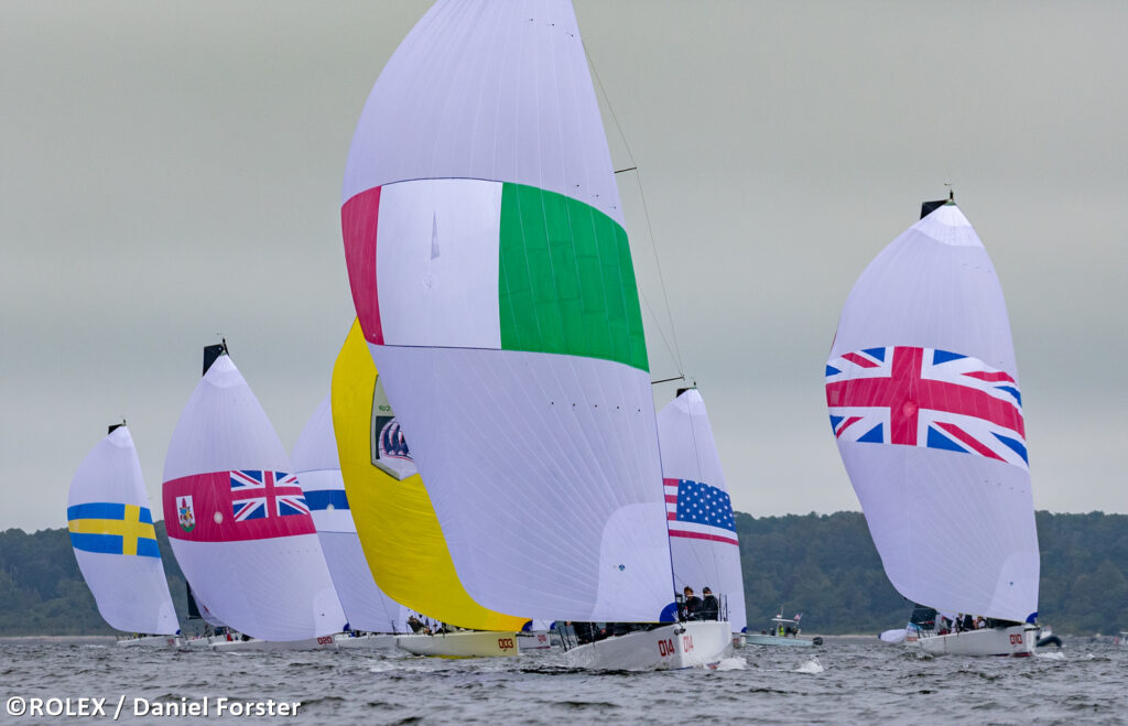 Fleet sailing downwind with kites, Italian boat leading fleet.