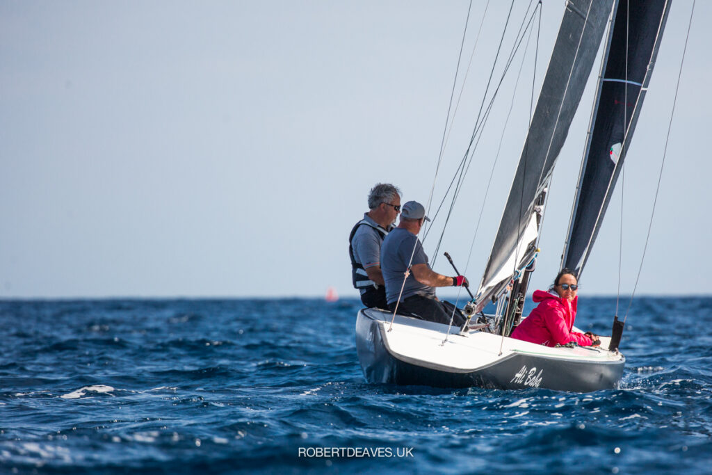 The stern of Ali Baba as they sail upwind. A crew member smiling back at the camera.