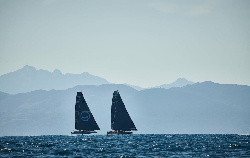 Zoulou and another boat sailing in a line, mountains in the backgrou.d