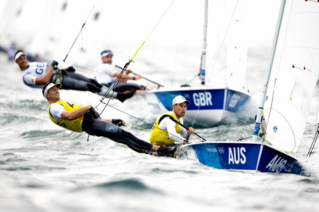 Mat Belcher and Will Ryan sailing upwind through chop, with GBR behind them.