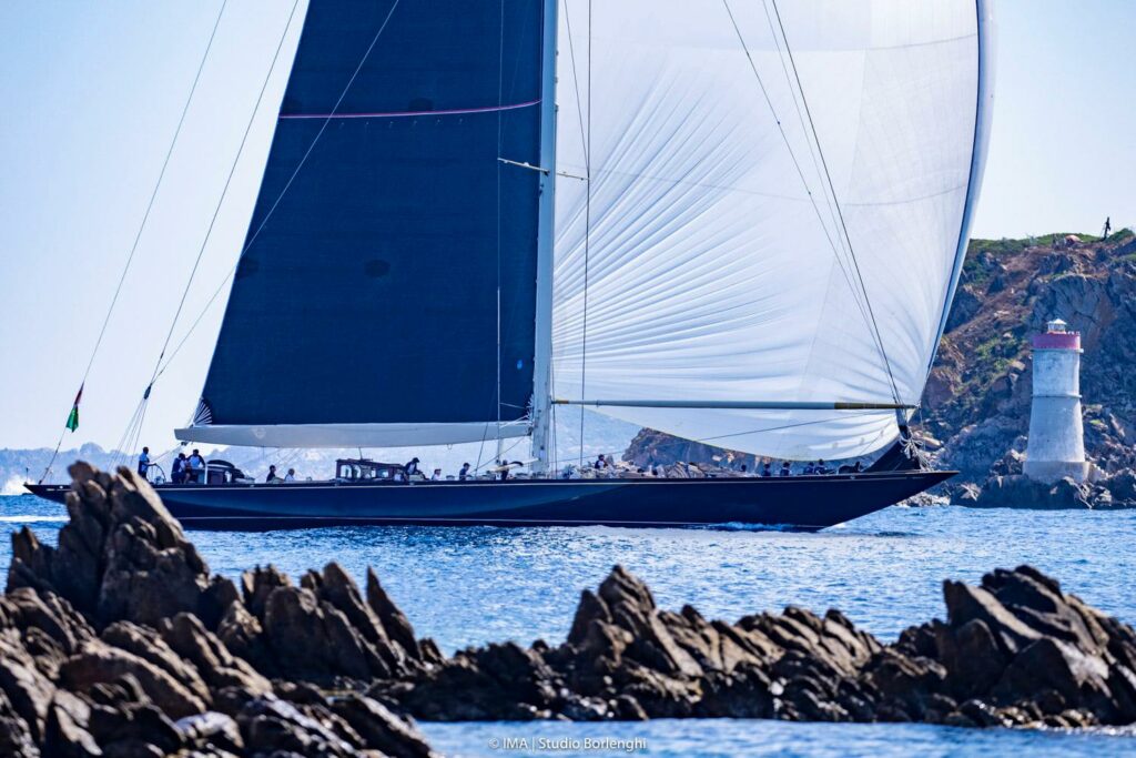 Topaz sailing downwind with kite, about to pass a lighthouse structure.