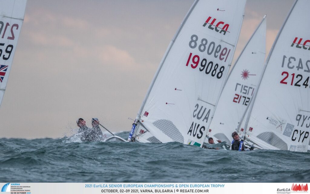 A sailor,sailing on a reach, coming up a big wave with a few sailors behind them.