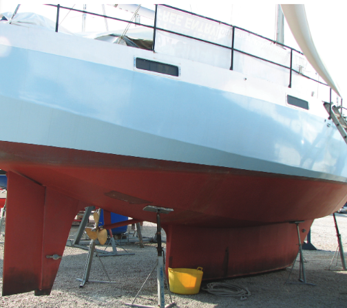 Boat on dry dock with red bottom and shallow keel.