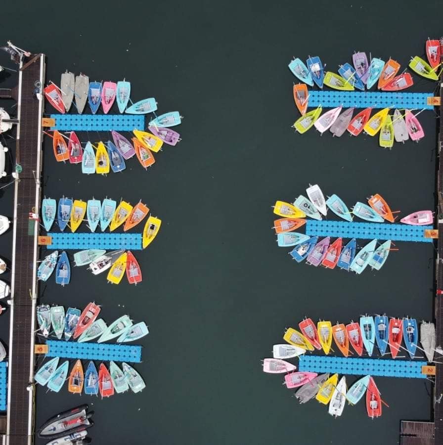 Aerial shot of dinghies tied up to the dock, multicoloured.