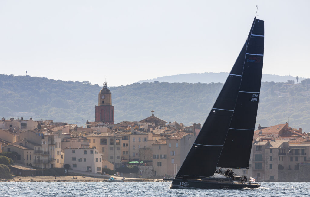 Yacht sailing upwind, passing village.