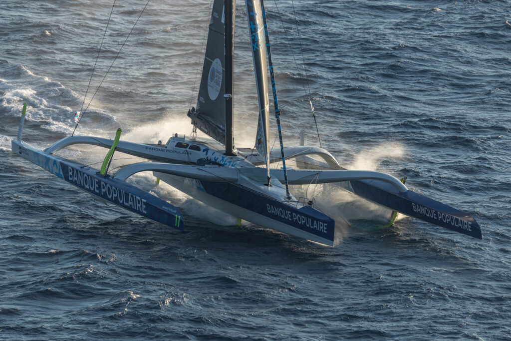 Aerial shot of a multihull sailing, creating a lot of wash.