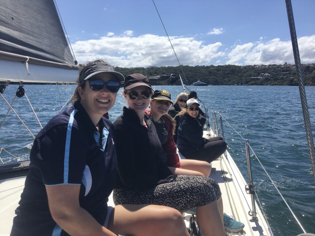 Crew smiling at camera, sitting on the side of the boat.