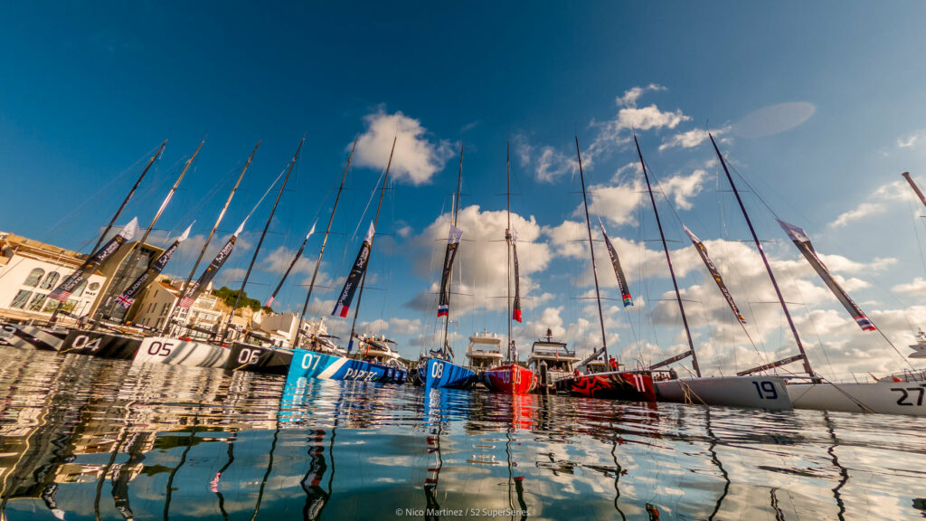 Boats lined up on the dock, sun reflecting on water.