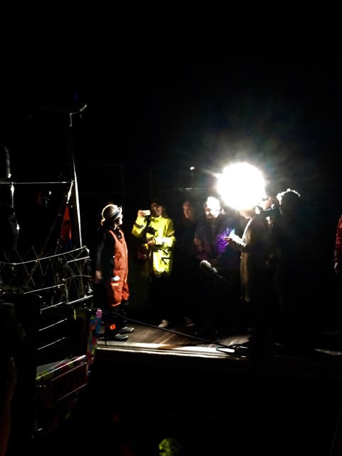 Pitch black, one light, Lisa Blair on the dock greeted by friends and family.