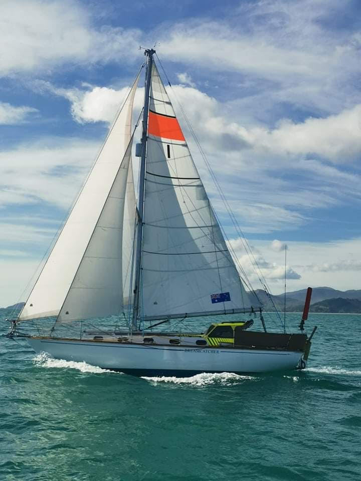 Dreamcatcher sailing with al sails up, mountains in the background.