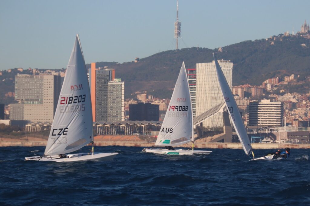 Three boats sailing on different tacks upwind, towards land.