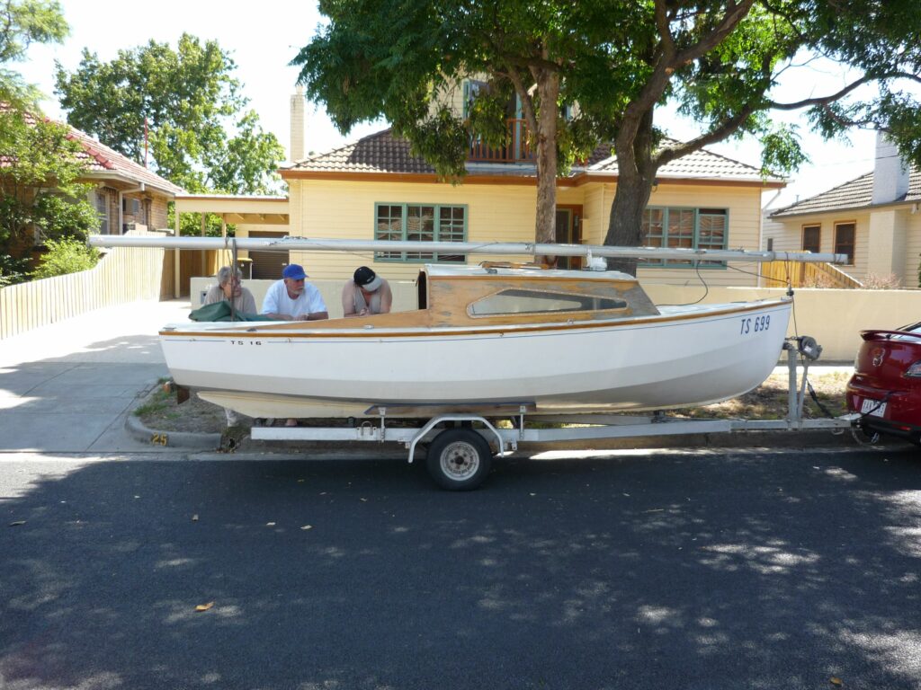 The Hartley on a trailer with three people leaning over it.