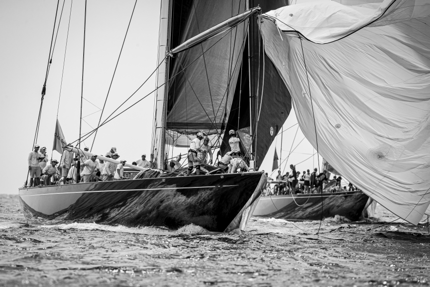 A boat sailing downwind, kite flapping, bow crew sorting out sails at the bow.