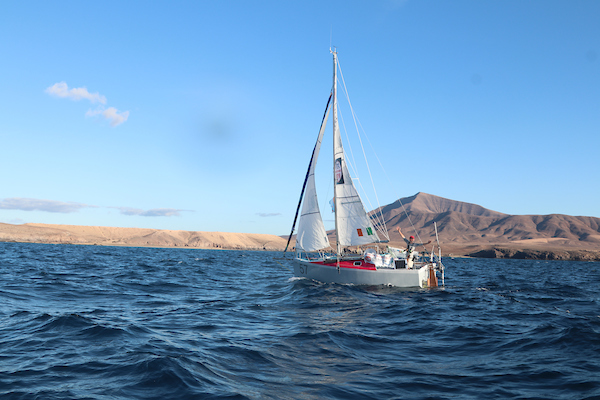 Jim Scofield sailing and waving at the camera. 