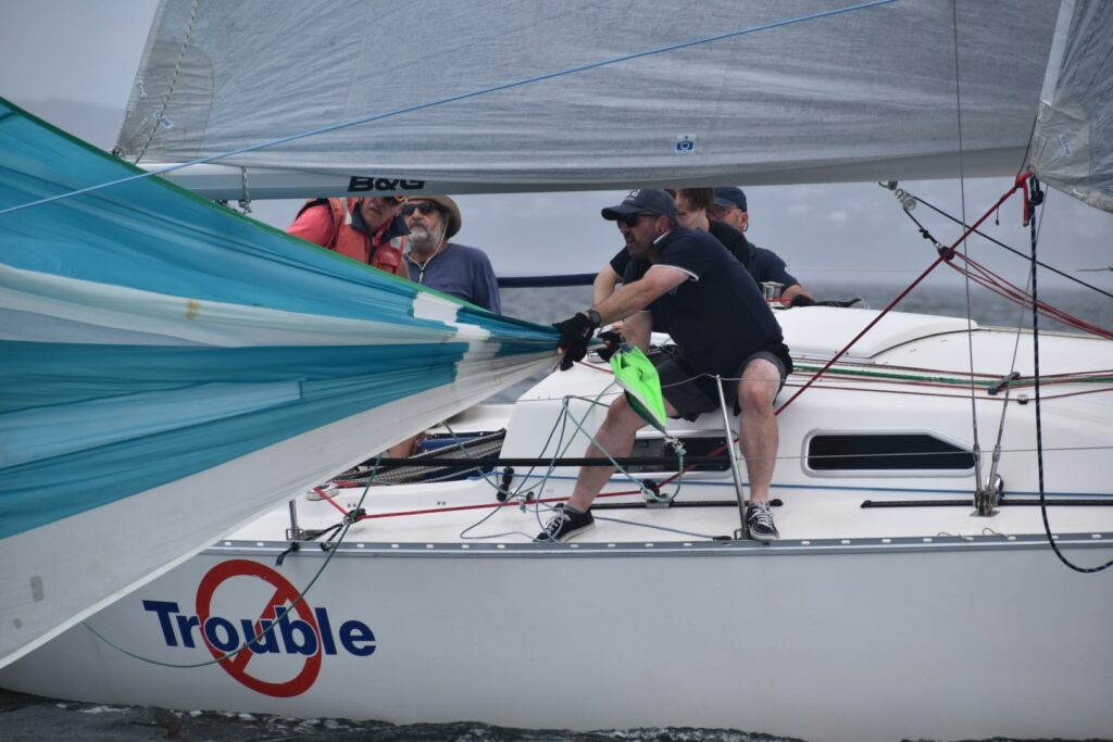 Person pulling in kite which is flying off the beams of the boat.