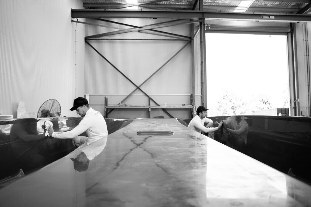 Black and white photo of people working on fibreglass.