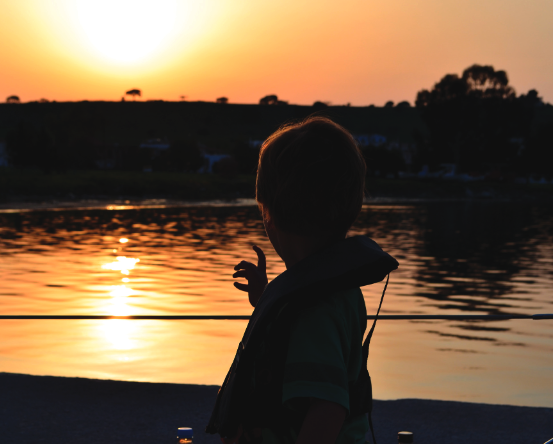 Kid on boat looking at sunset.