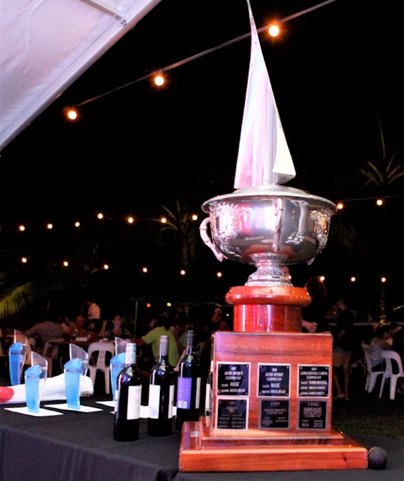 Trophy and awards on a table, with people sitting on tables in background.