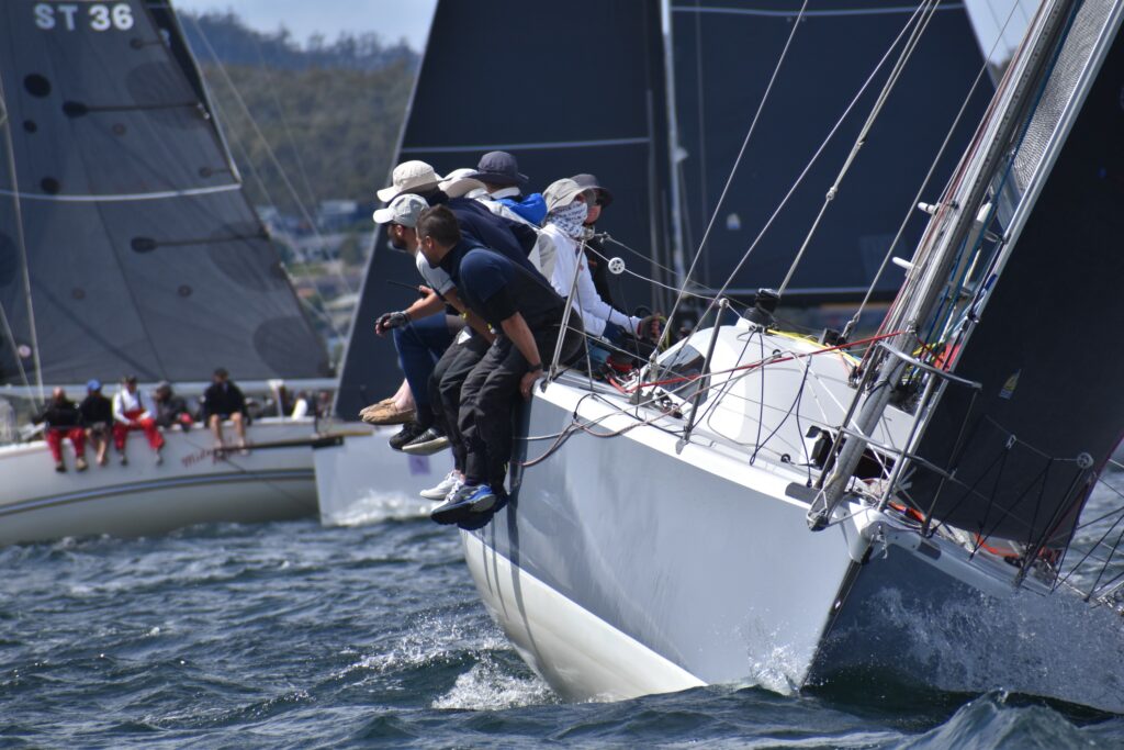 Heatwave sailing upwind, crew on the side, two boats behind them on opposite tacks.