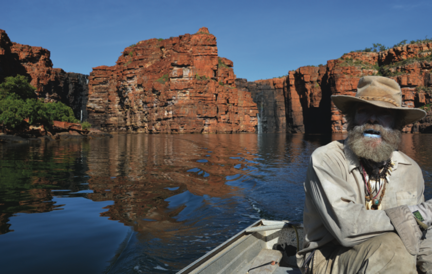 Jon on small dinghy motoring through the falls, big red rocks surround them.