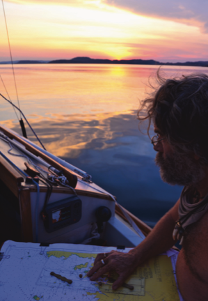 Holding paper chart on the boat at sunset.