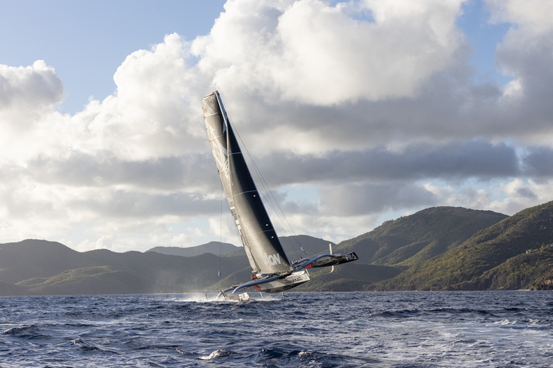 Maserati sailing upwind, windward hull in the air, hills in the background.