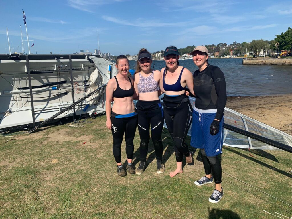 Jess Stephenson, Haylee Kellam, Tilly Lang, Katherine Bennett on the beach with a skiff behind them.