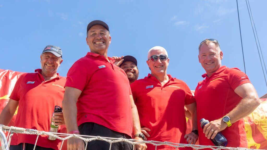 Crew on board Qingdao, smiling, looking down at the camera.