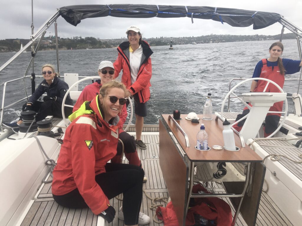 Crew smiling in the cockpit as the yacht is sailing.