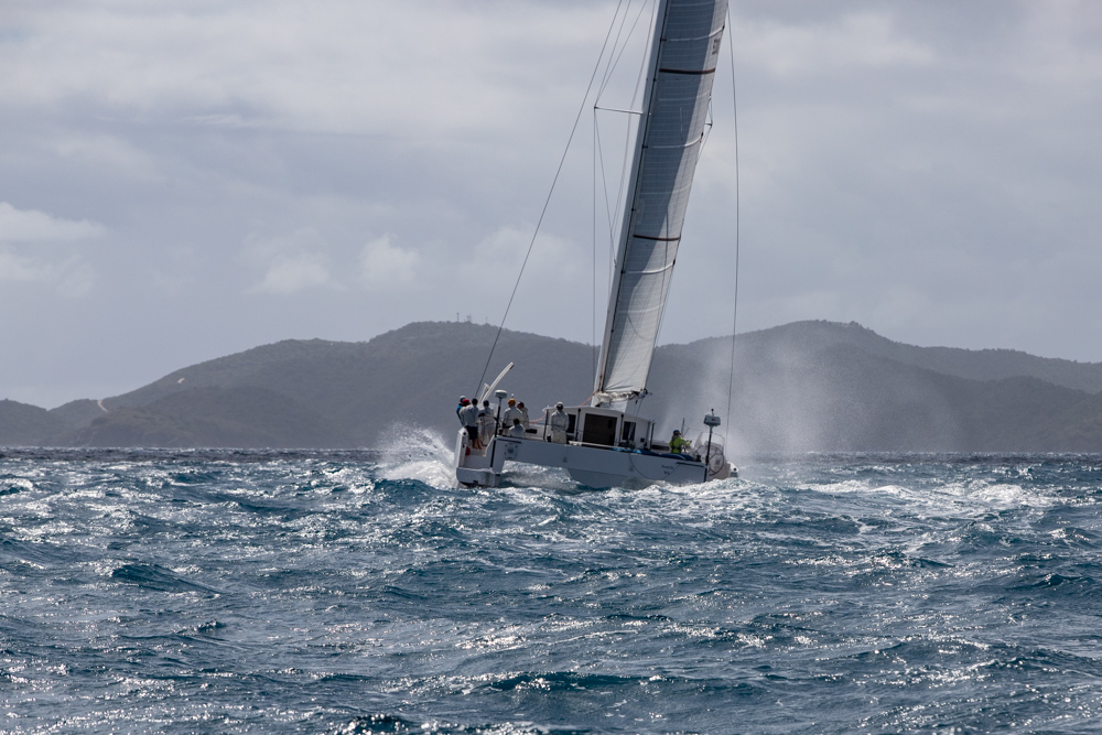 Catamaran sailing upwind in chop, spray coming off the boat.