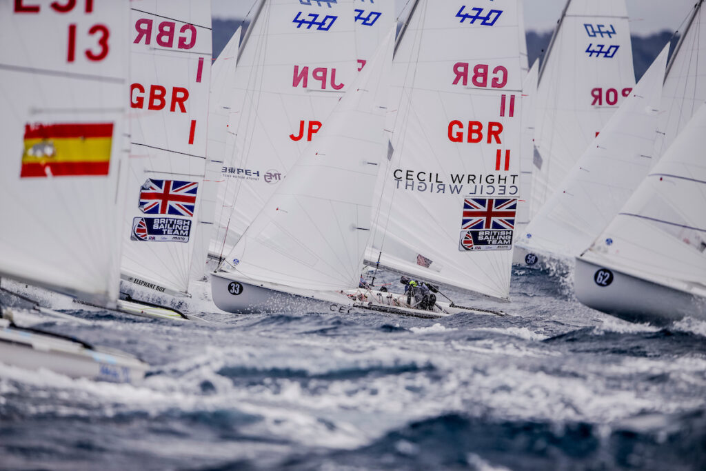 470 fleet sailing upwind after race start.