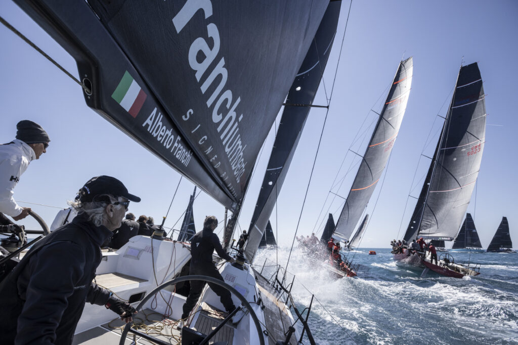 Fleet sailing upwind, other in front rounding top mark.