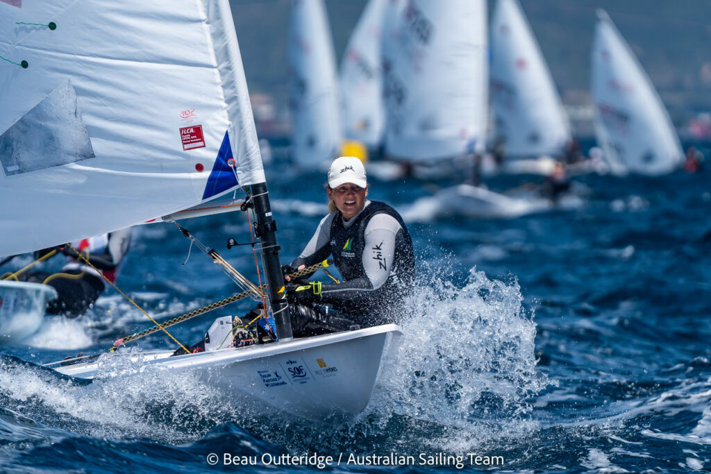 Elyse Ainsworth sailing on a reach with boats behind her.