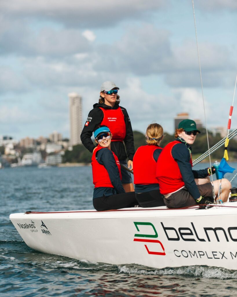 Bickford steering while standing. Crew smiling.