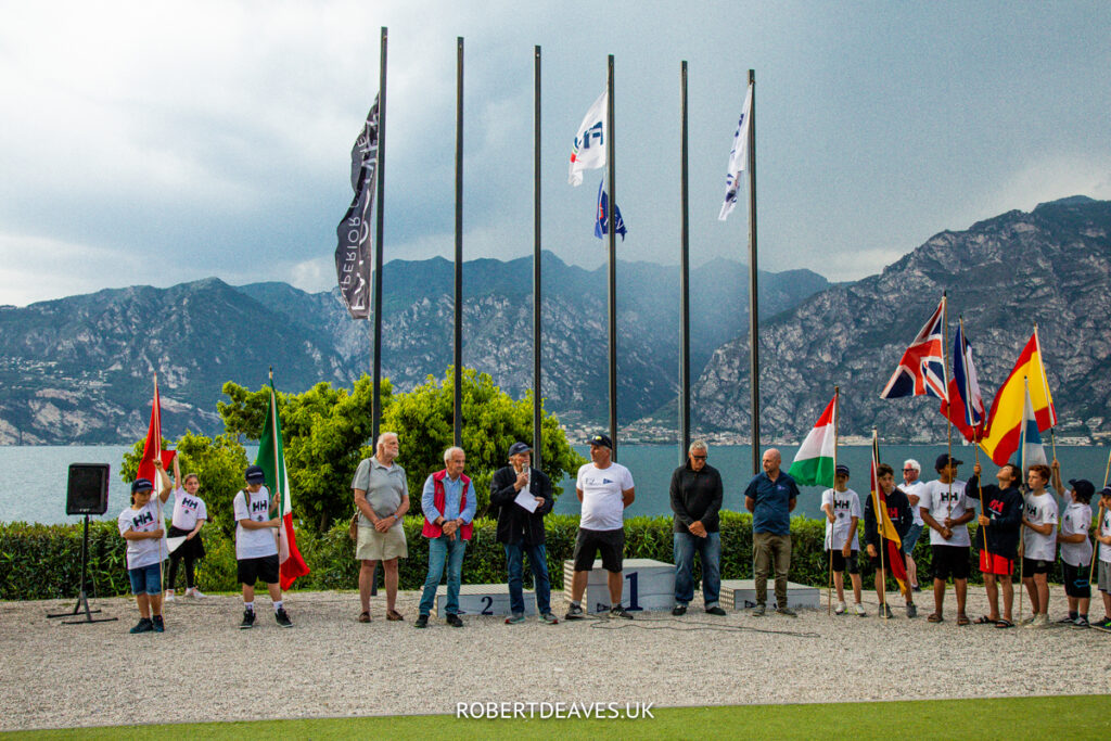 Opening ceremony in front of flag pole with mountains in the background.