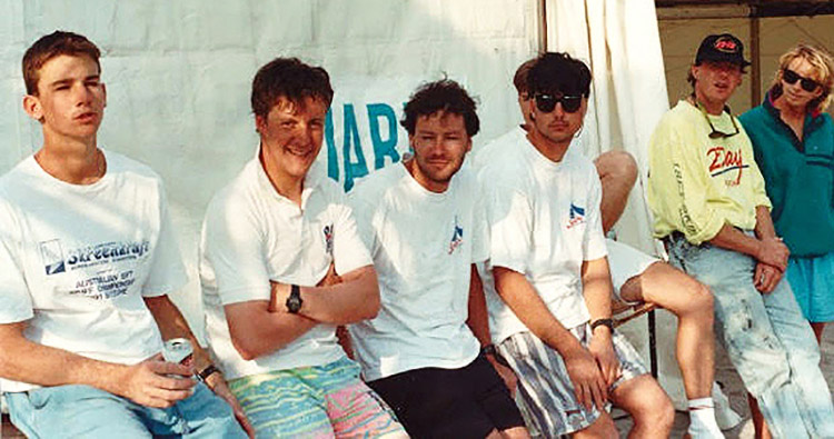 A group of people sitting on the side of a skiff in the boat park.