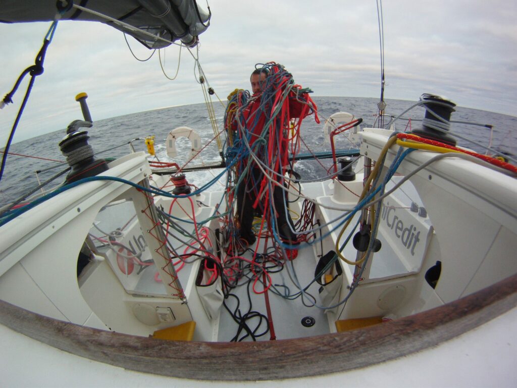 Sailor holding clumps of tangled sheets in cockpit.