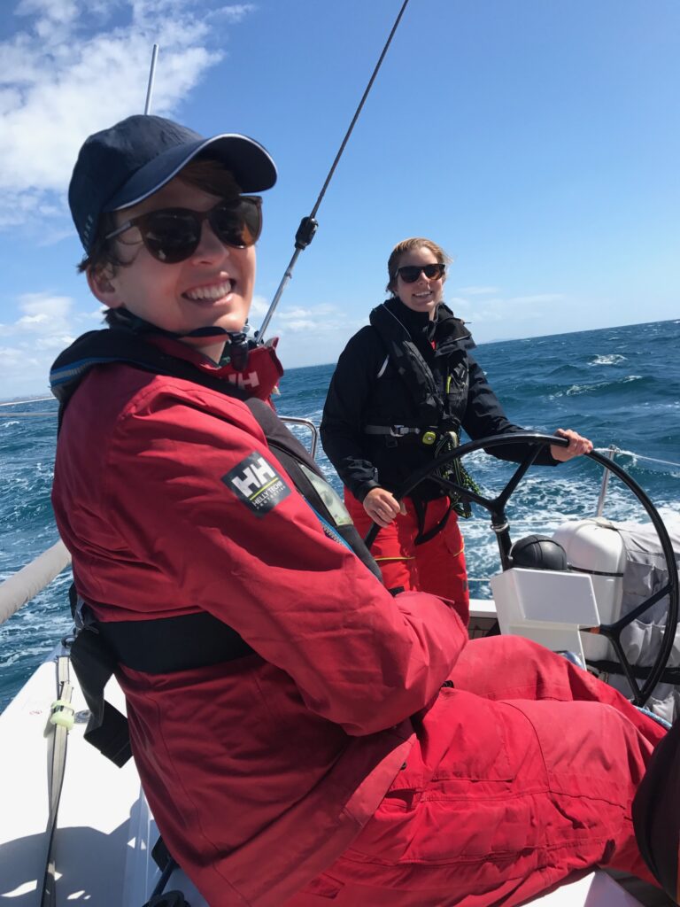 One person steering, the other person sitting ahead of the wheel, smiling.