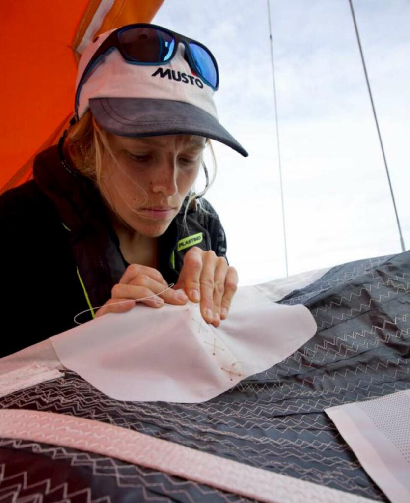 Catheryne Langford repairs a chafed area on Explorer’s cruising code sail. Credit: OGR2023 / Explorer