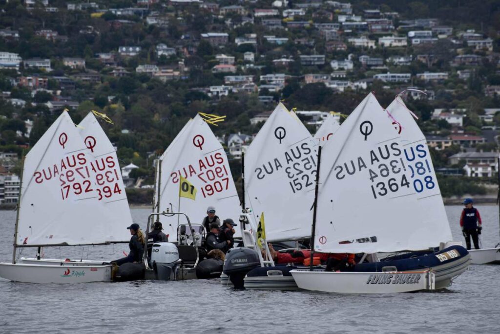 Optimist sailors waiting for the breeze with their coaches Credit Jane Austin